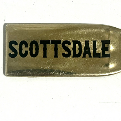Close-up of a flattened brass .308 casing engraved with Scottsdale in black lettering