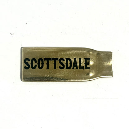 Flattened brass .308 casing engraved with Scottsdale in black lettering on a white background