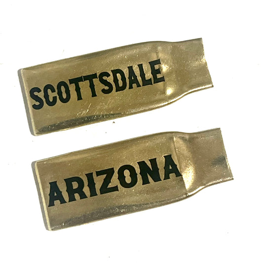2 flattened brass .308 casings engraved with Scottsdale and Arizona in black lettering, lying on a white background