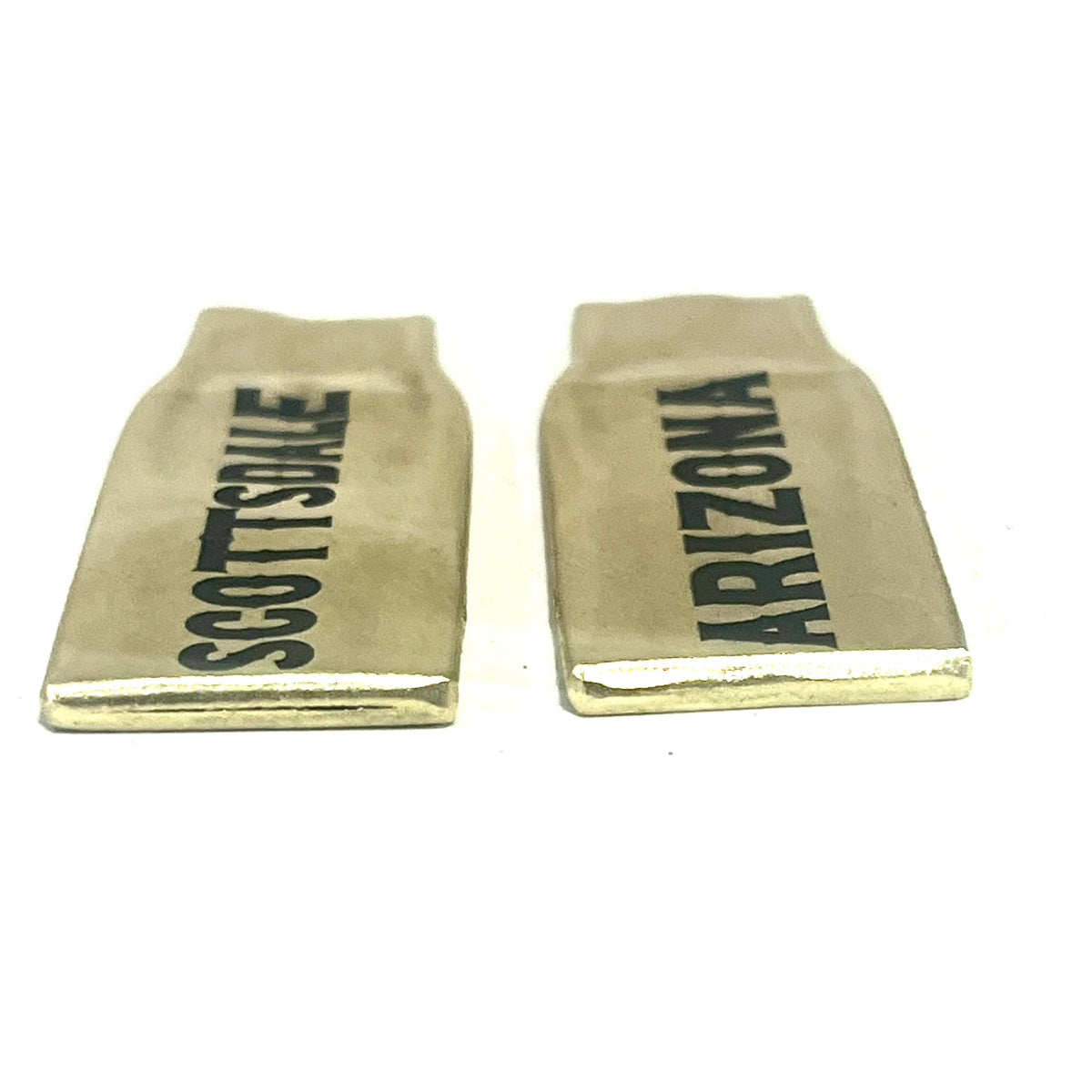 2 flattened brass .308 casings engraved with Scottsdale and Arizona in black lettering, lying on their sides