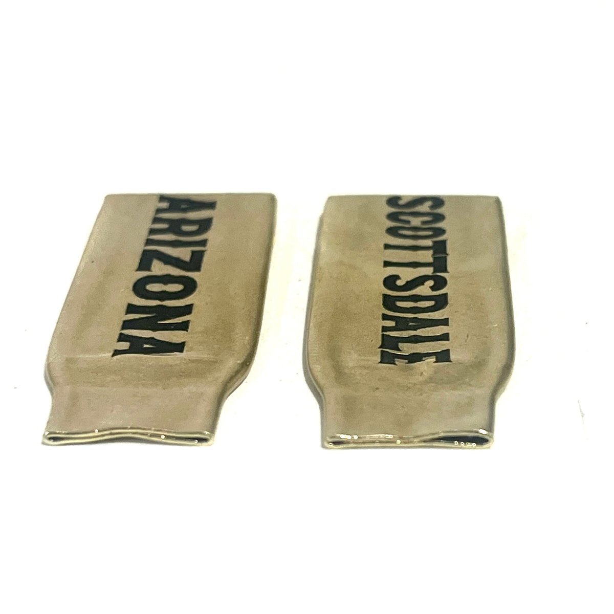 2 flattened brass .308 casings engraved with Arizona and Scottsdale in black lettering, standing side by side