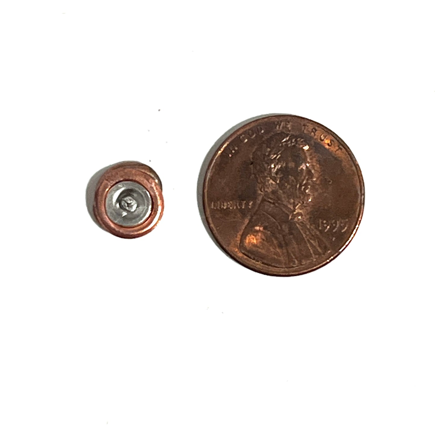 A flattened primer components stud shown next to a US penny for size reference on a plain white background.