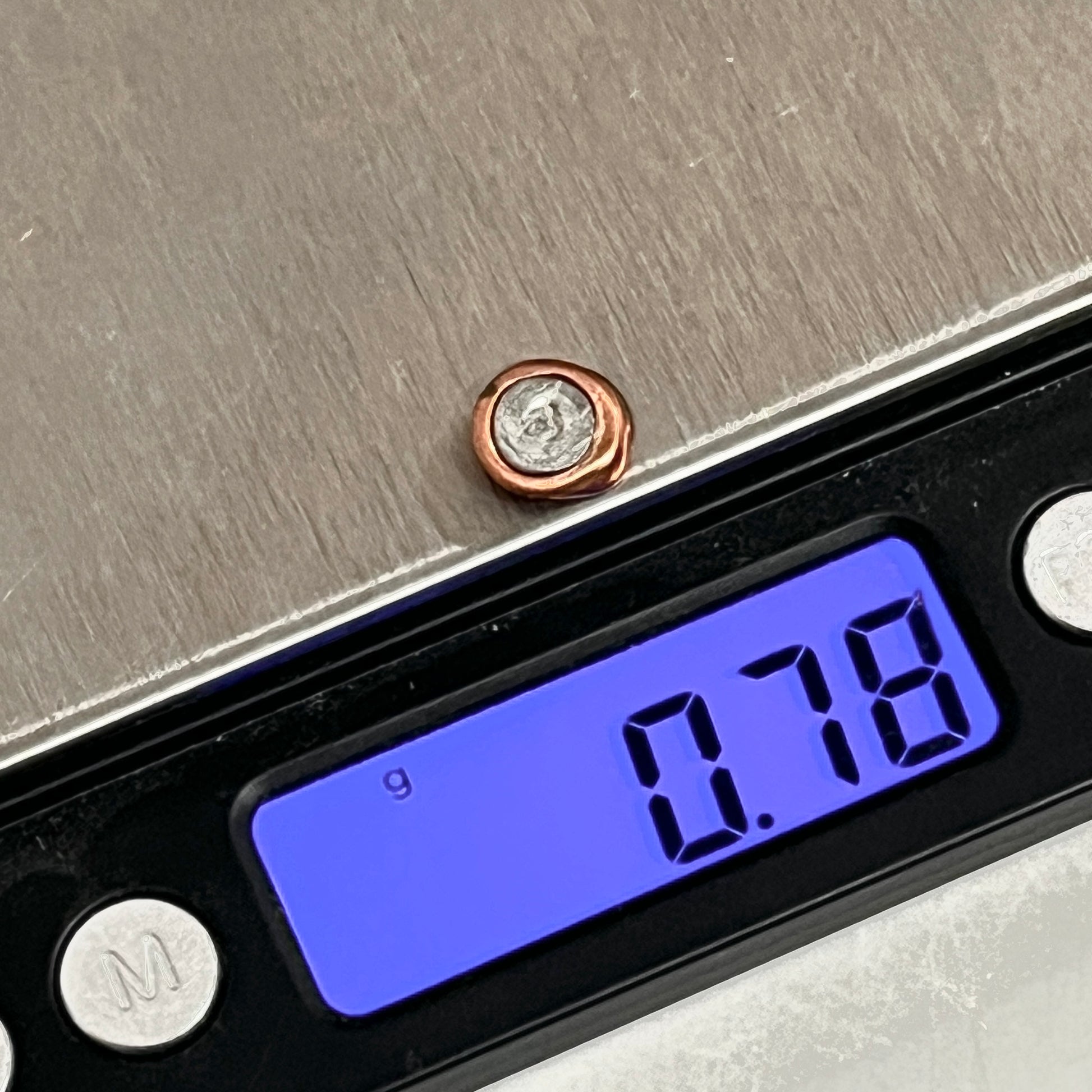 Digital scale displaying 0.78 grams for a single copper and silver flattened primer disc.