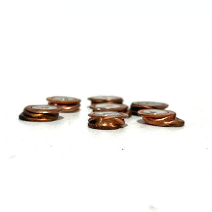 Three small stacks of flattened two-tone copper and silver primers arranged in a line on a white background.
