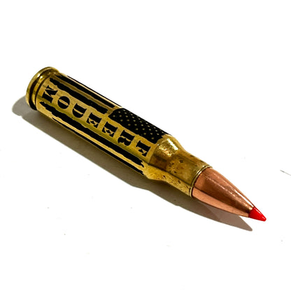 Brass .308 casing with red bullet tip angled closely, showing 'FREEDOM' engraving and flag stripes on white