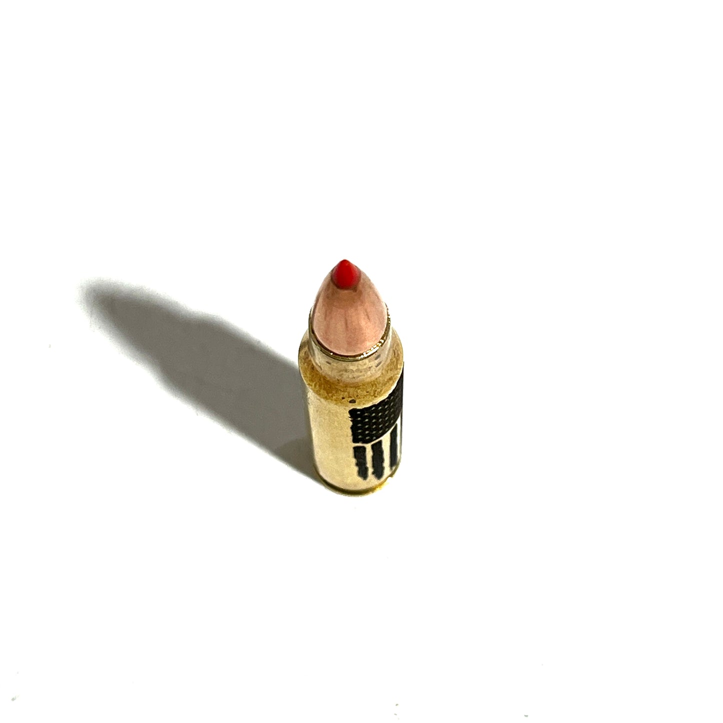 Brass .308 shell with red tip and 'FREEDOM' engraving, viewed from above with a long diagonal shadow