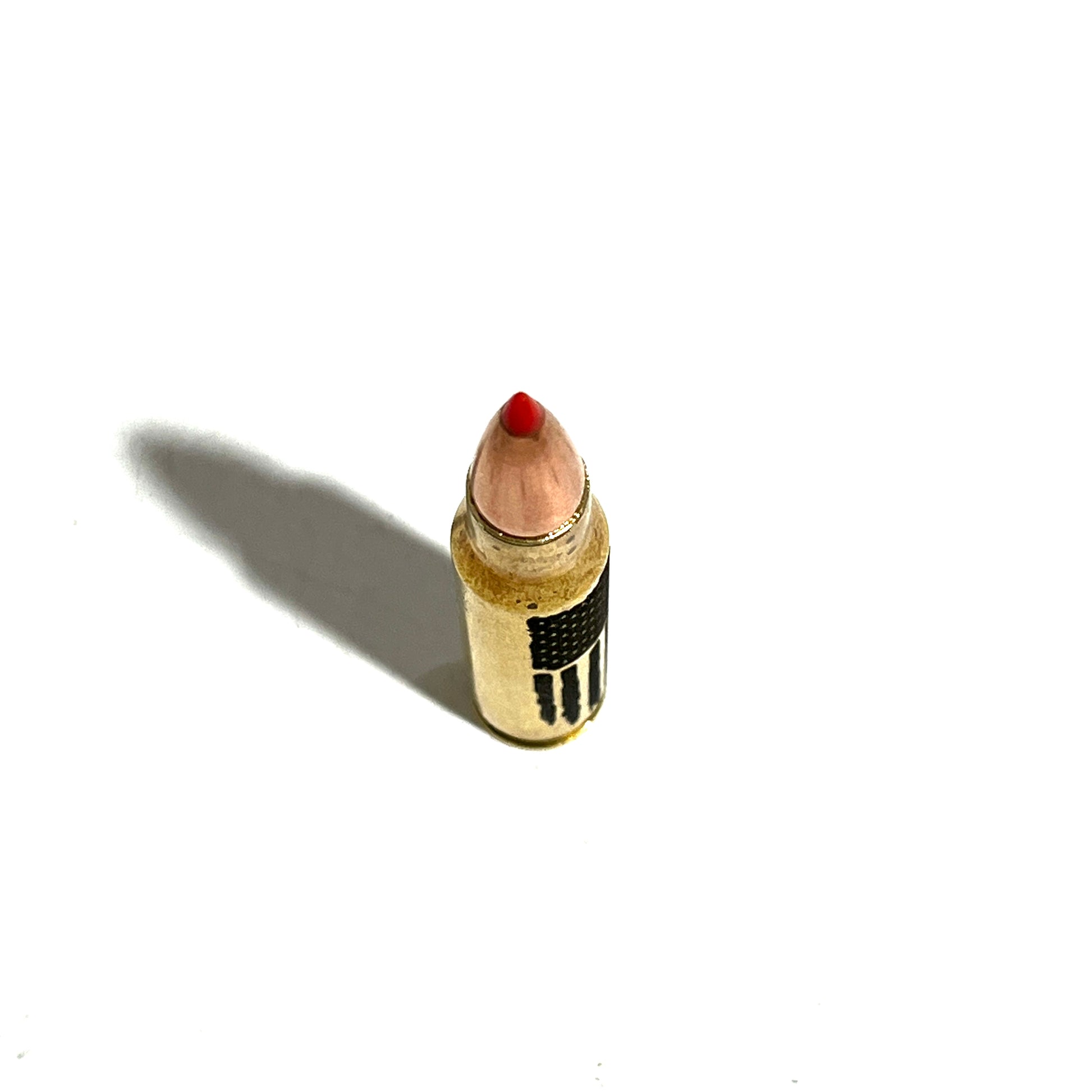 Brass .308 shell with red tip and 'FREEDOM' engraving, viewed from above with a long diagonal shadow