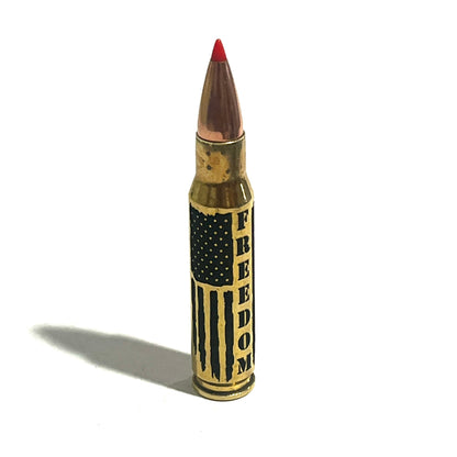Engraved brass .308 shell with red tip and 'FREEDOM' text, standing upright on white with a long shadow