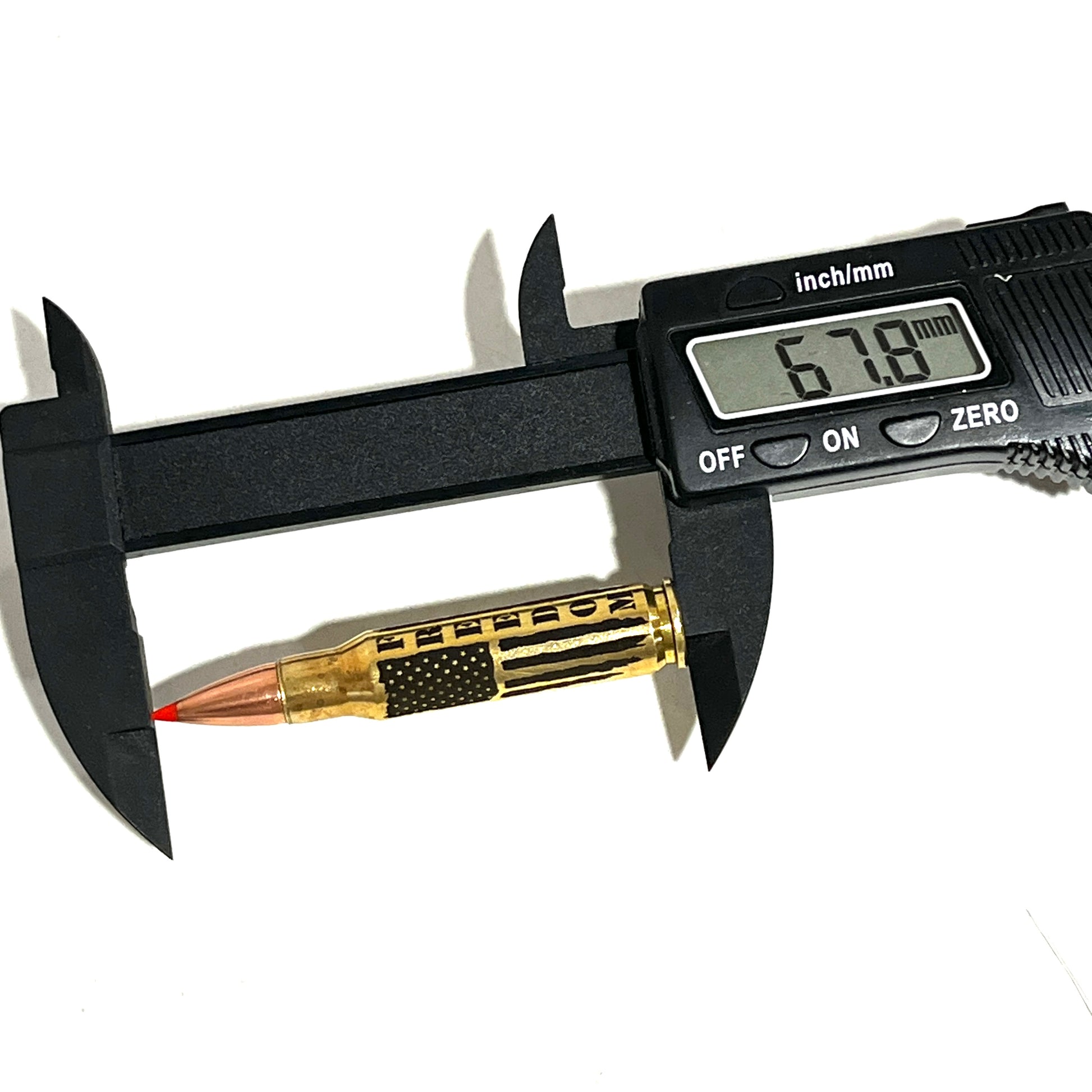 Digital caliper measuring an engraved 'FREEDOM' brass .308 casing, showing a 67.8 mm length reading