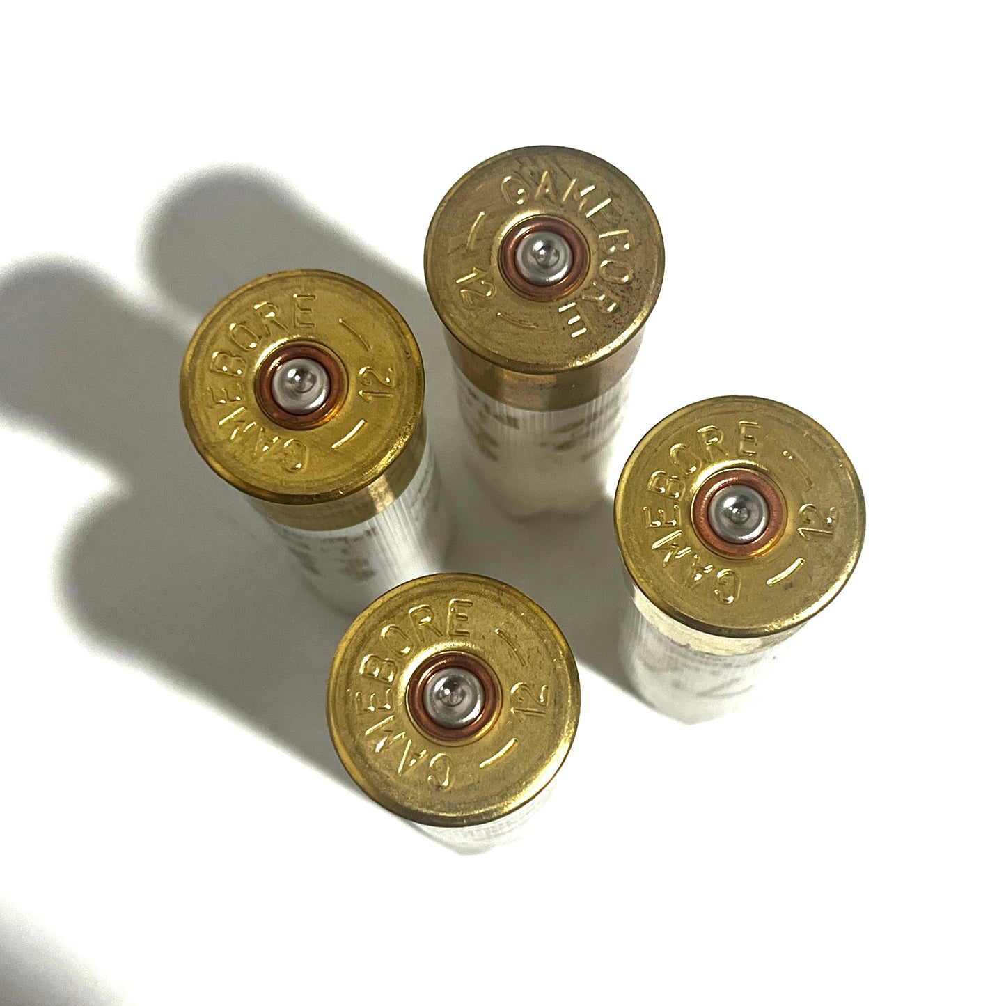 Four gold Gamebore 12 gauge brass bases viewed from above on a white background