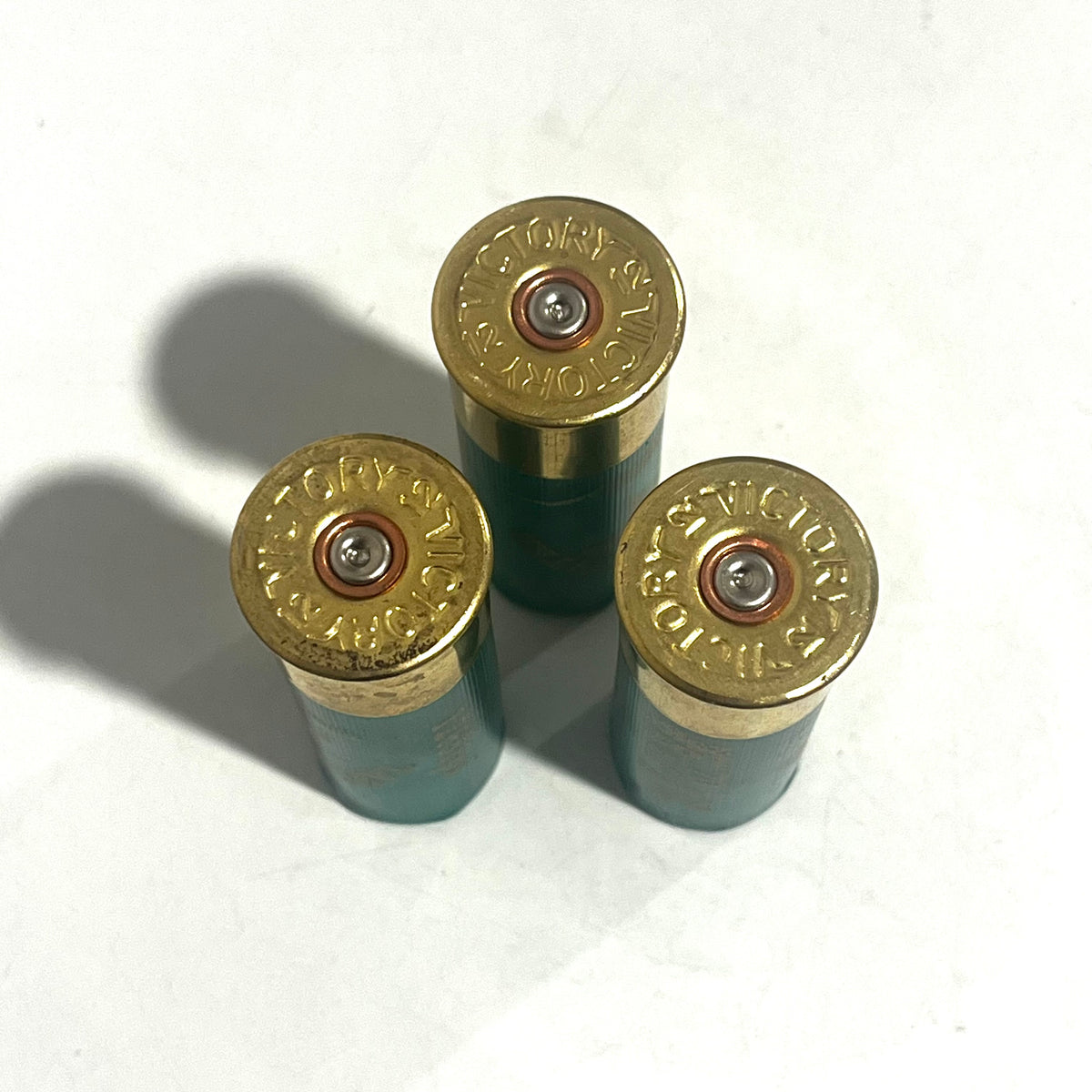 Three green empty dummy rounds shown base-up with Victory stamped on the brass headstamps