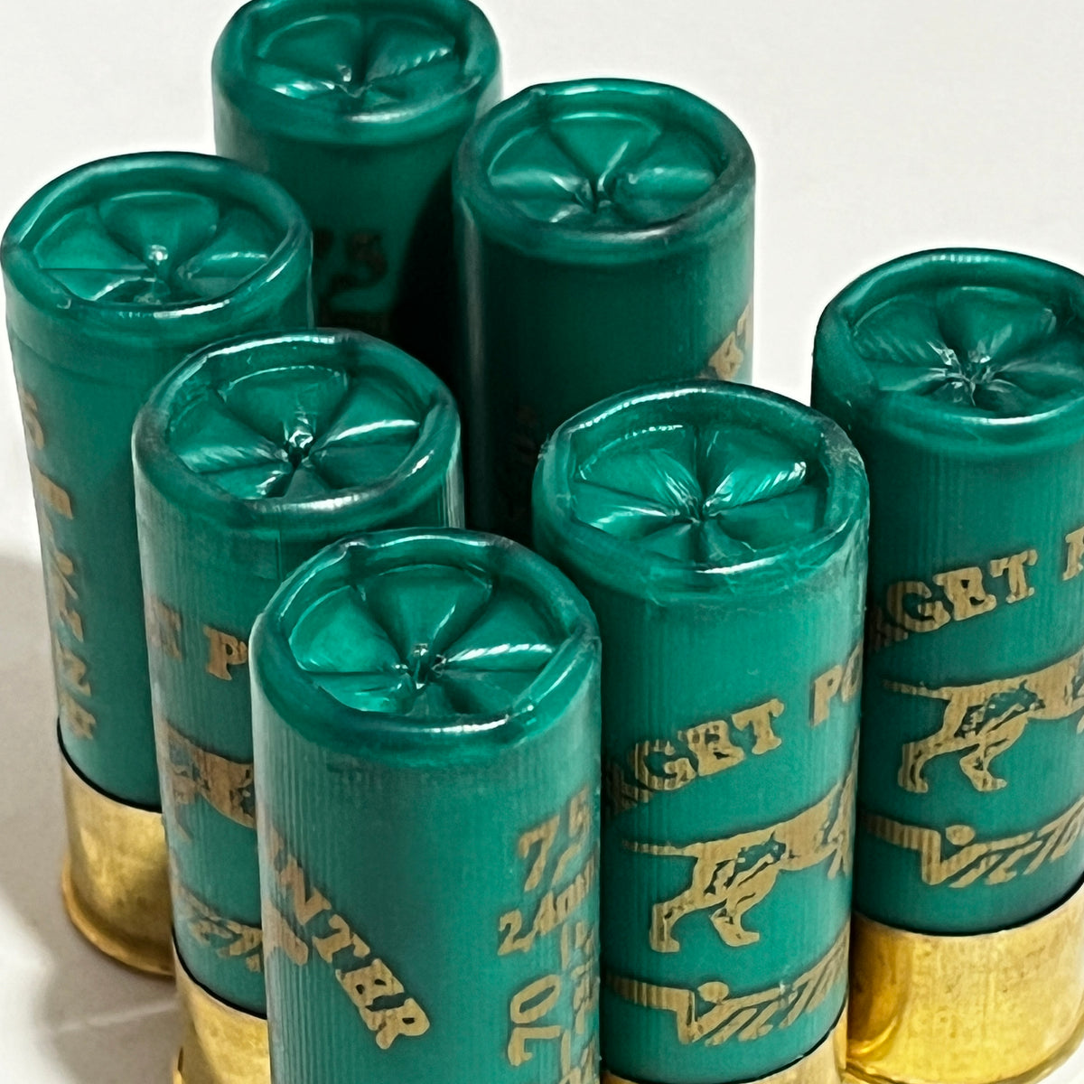 Seven green once-fired shotshells with crimped star-fold tops, clustered together and viewed close up