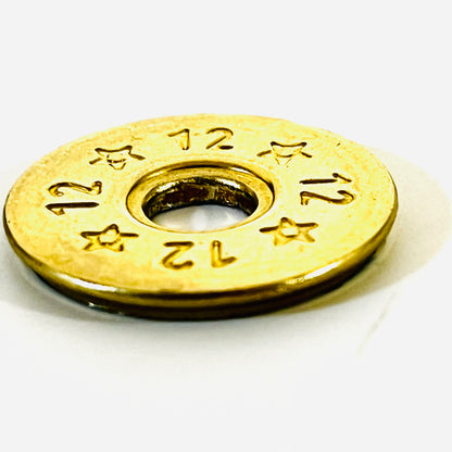 Close-up of a single deprimed 12 gauge brass shotgun shell slice with 12 and star stamped design, angled to show its edge
