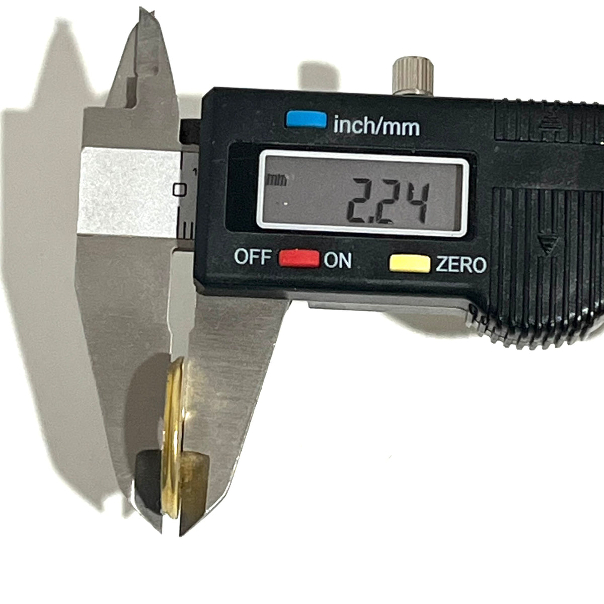 Digital caliper measuring the thickness of a deprimed 12 gauge brass shotgun shell slice at 2.24 mm