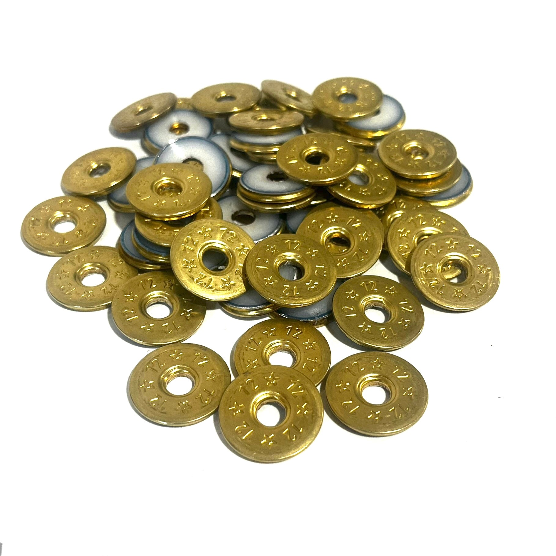 A pile of deprimed 12 gauge shotgun shell slices with brass 12 and star stamped designs and open center holes