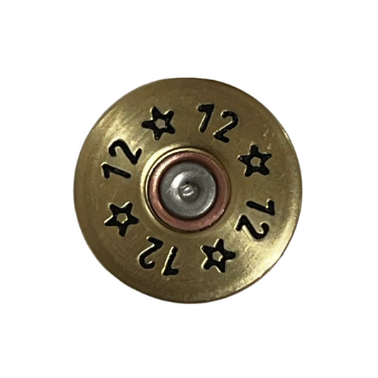 Close-up of a round gold brass 12 gauge shotgun shell slice stamped with 12 and star designs around a silver primer