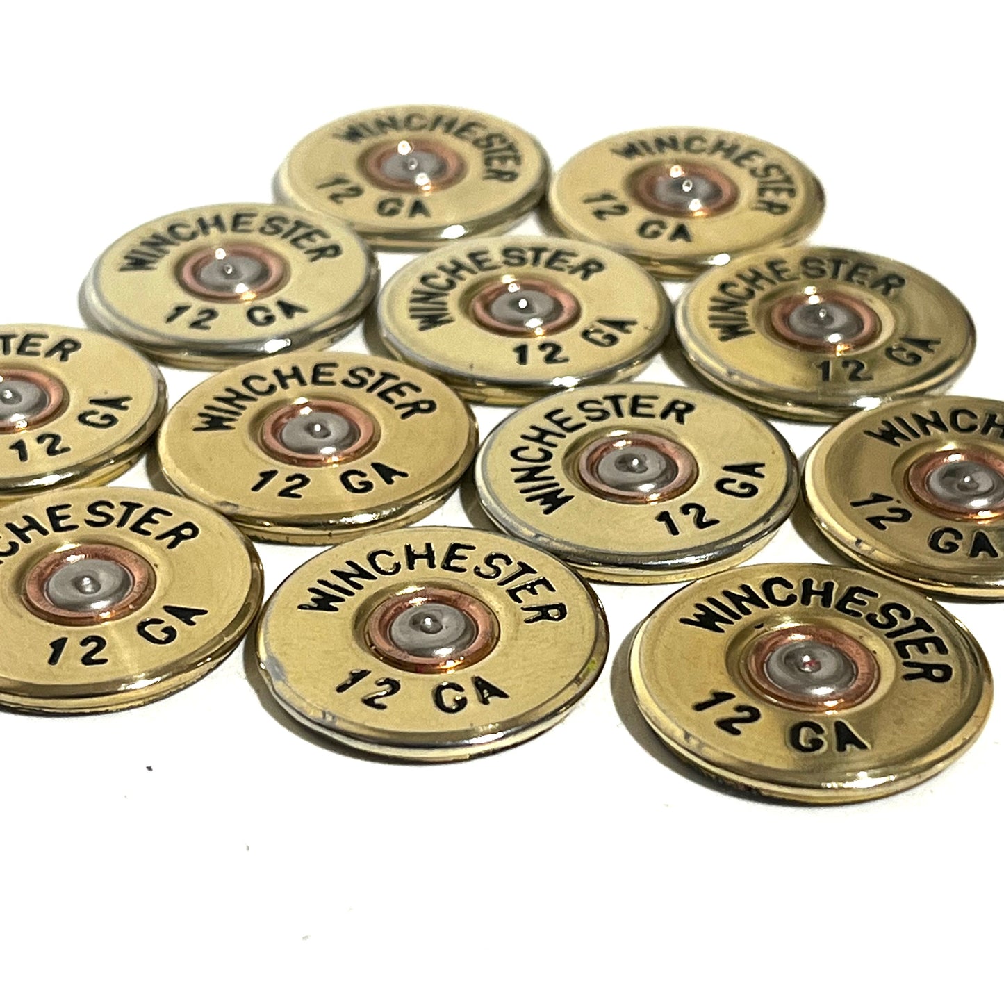 11 gold Winchester 12 GA shotgun shell slices with black lettering arranged on a white background