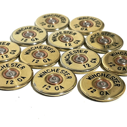 11 gold Winchester 12 GA shotgun shell slices with black lettering arranged on a white background