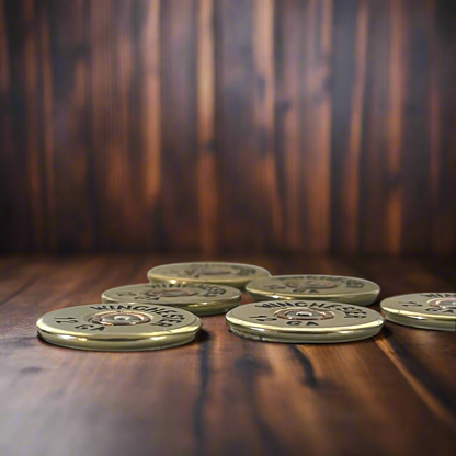 6 gold Winchester 12 GA shotgun shell slices on a dark wood surface with a blurred wood background