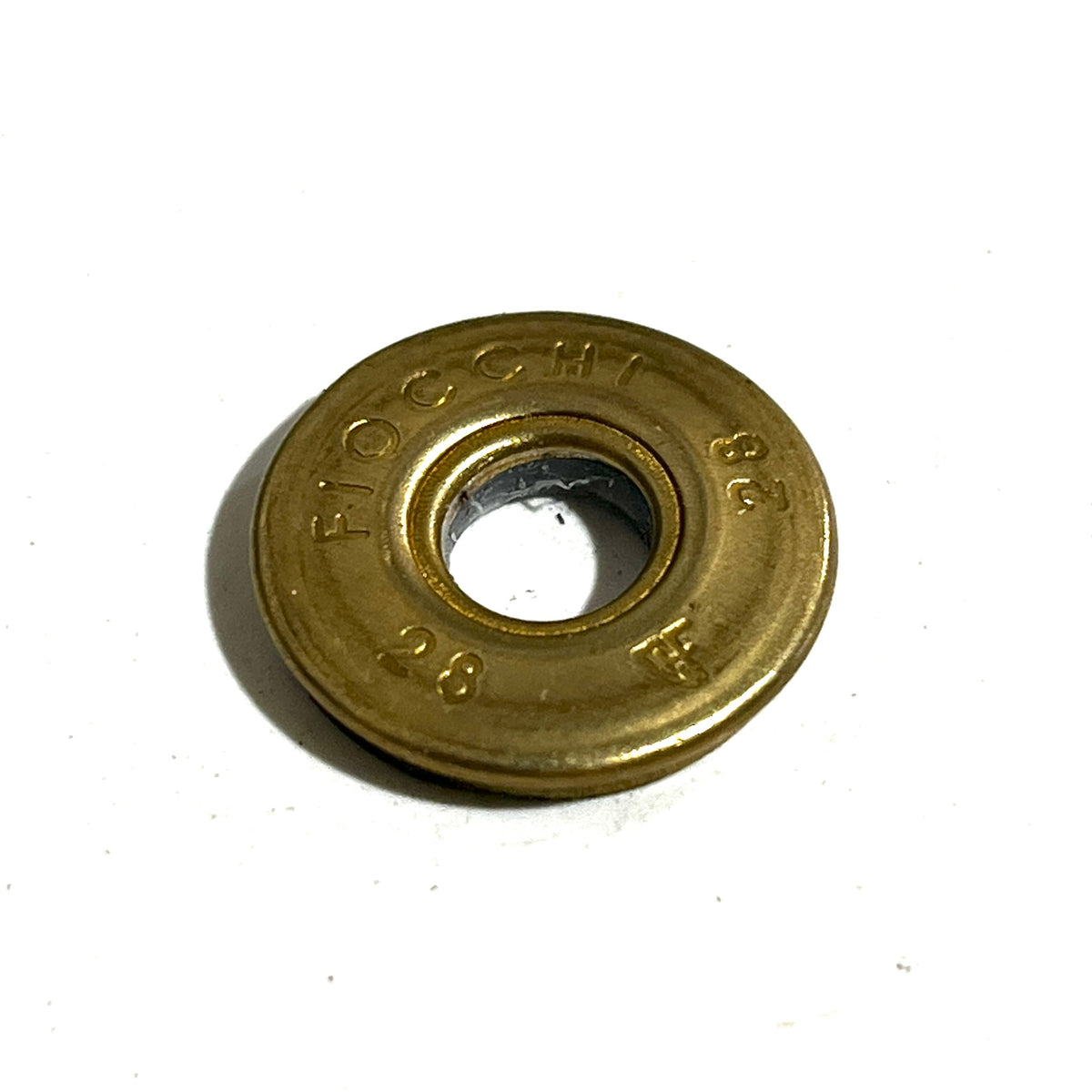Close-up of a Fiocchi 28 gauge shotgun shell slice showing a drilled deprimed center