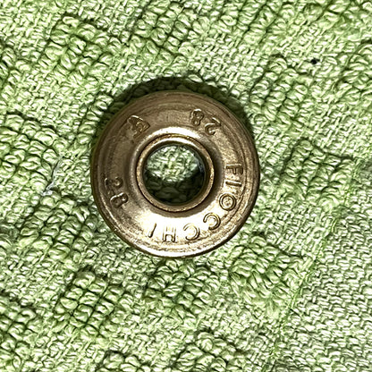 Close-up of a gold brass Fiocchi 28 gauge shotgun shell slice on a green cloth background