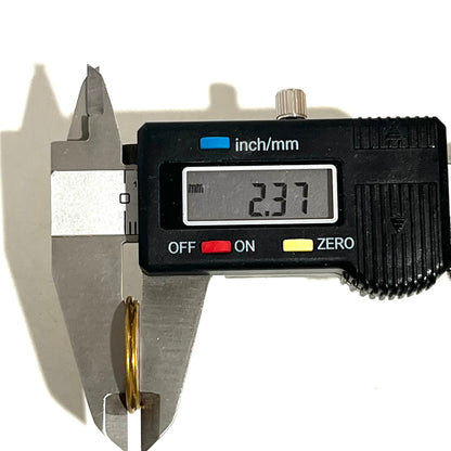 Digital caliper measuring the thickness of a gold shotgun shell slice showing 2.37 mm
