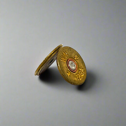 2 gold Winchester 12 gauge shotgun shell slices leaning against each other showing a brass headstamp