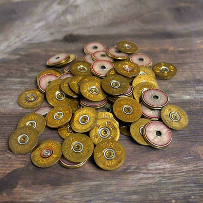Pile of gold Winchester 12 gauge shotgun shell slices with red and cream centers scattered on a wood table