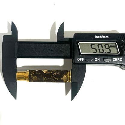 Digital caliper measuring the length of a brass rifle casing engraved with a gothic skull design at 50.9 mm