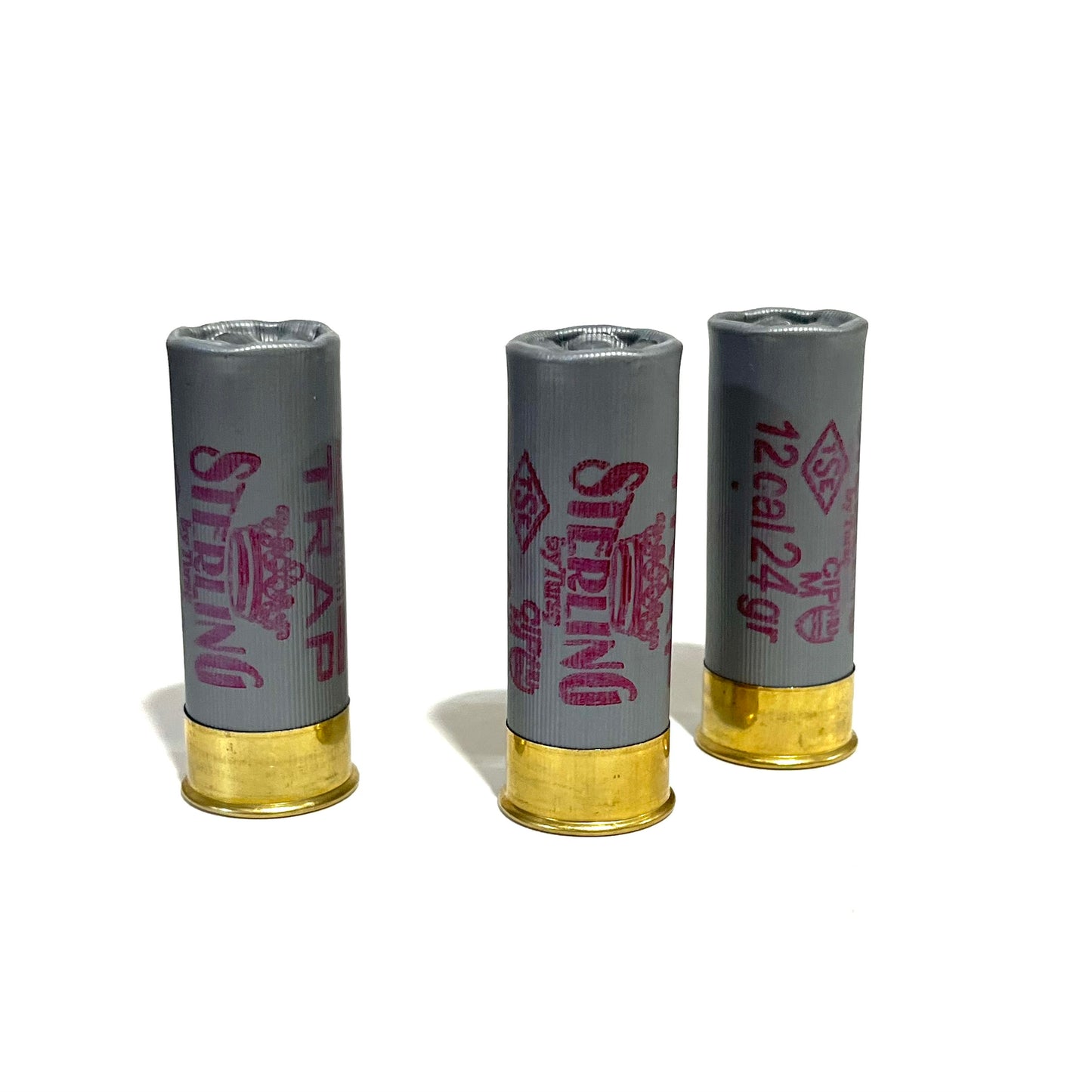 3 gray Sterling Trap 12 gauge shotgun shells standing upright with brass bases and pink text on a white background