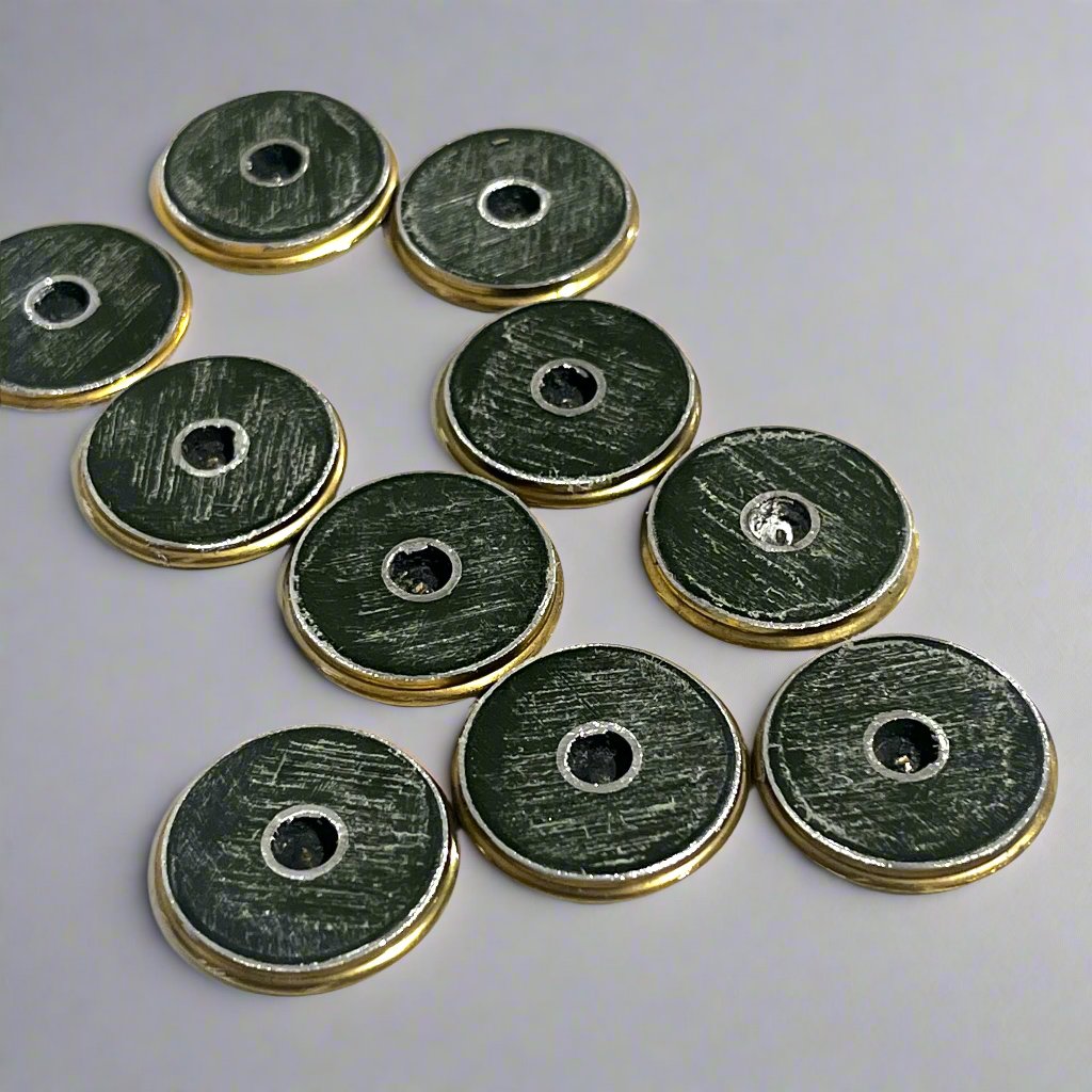 10 round brass shotgun shell slices viewed from the top showing scratched green paint and drilled holes