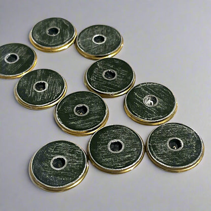 10 round brass shotgun shell slices viewed from the top showing scratched green paint and drilled holes