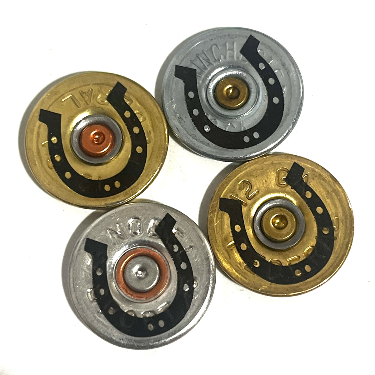Four mixed gold and silver 12 gauge shotgun shell slices with black engraved horseshoe designs on a white background