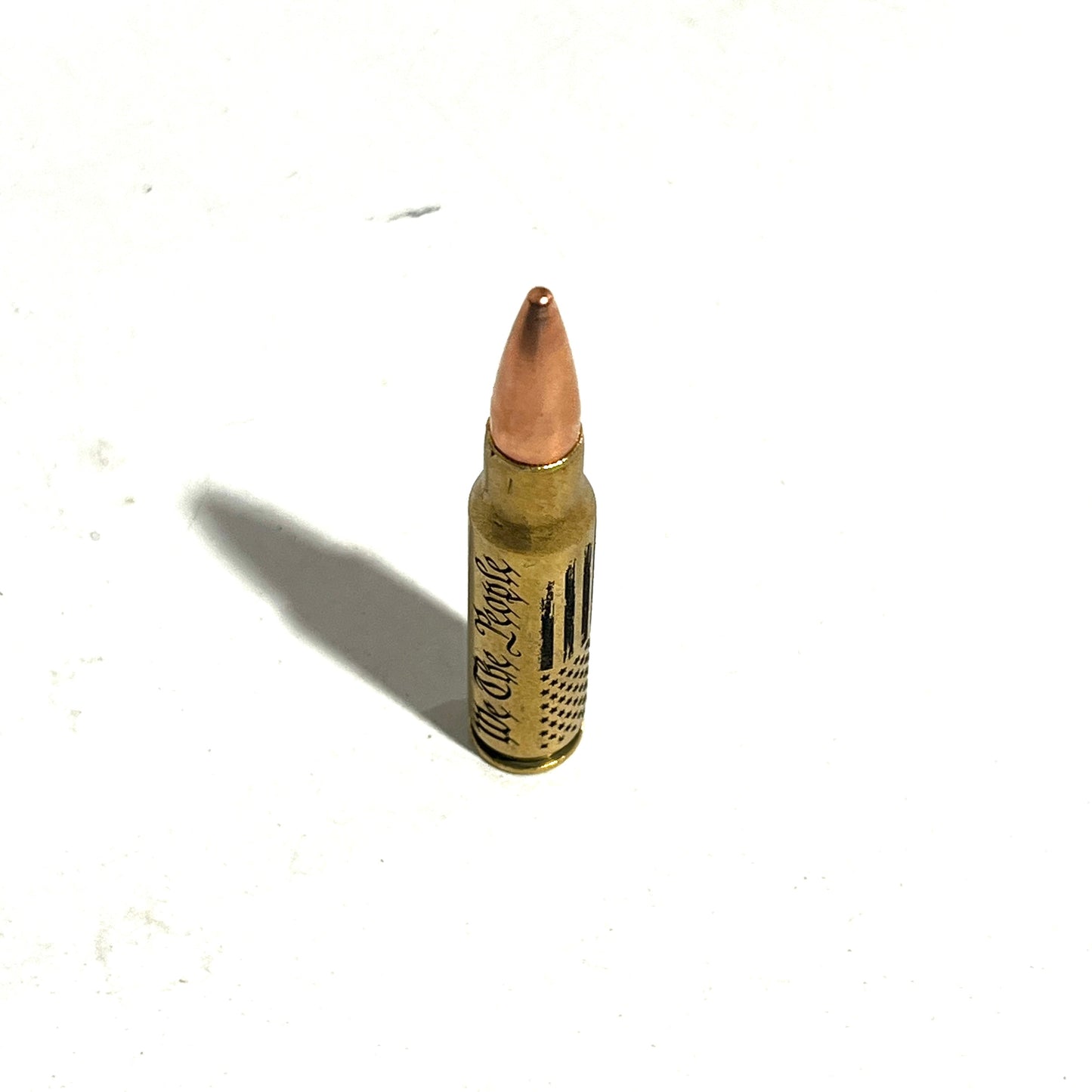 Inert 308 Winchester dummy round with We The People and flag engraving for desk display or collection.
