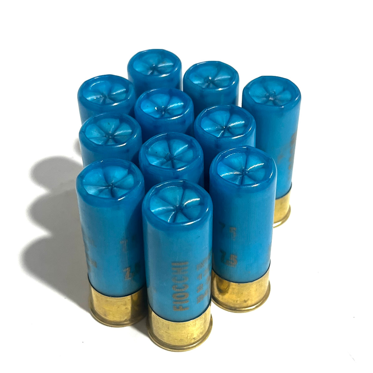 Ten light blue 12 gauge shotgun shell hulls standing upright showing closed star-folded crimp tops