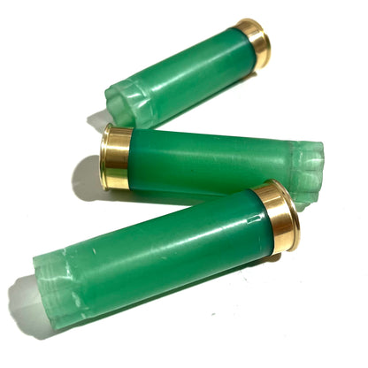 3 light green 12 gauge shotgun shell hulls with gold bases, lying at different angles on a white background