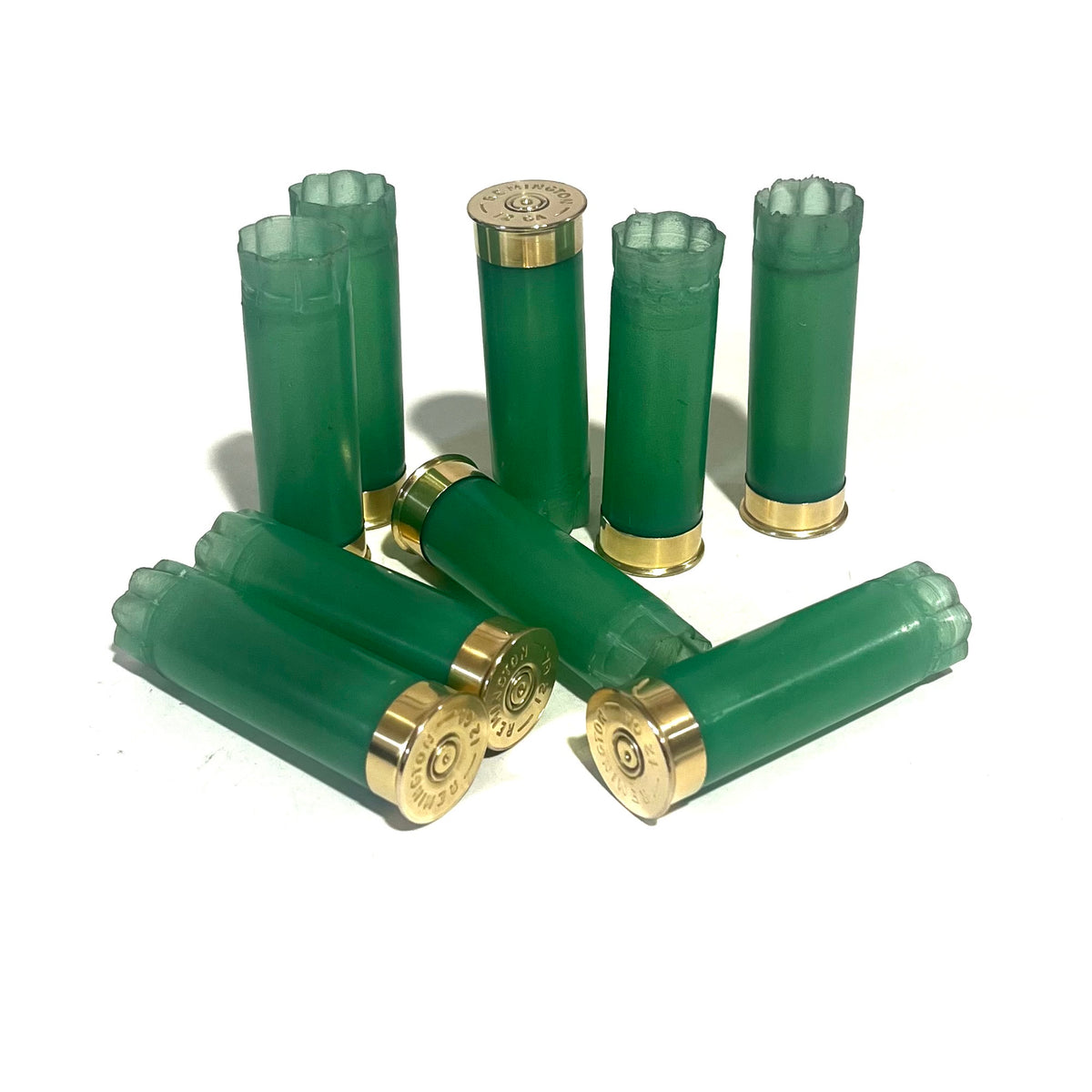 8 light green 12 gauge shotgun shell hulls with gold bases, standing and lying on a white background