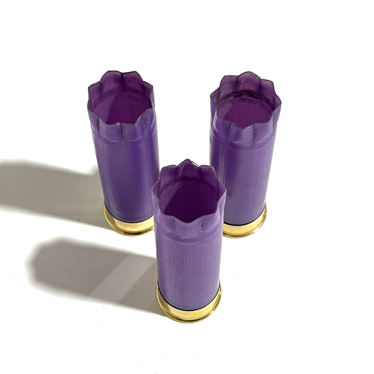 Three light purple casings standing upright in a triangle arrangement, all showing open 8 star crimped tops