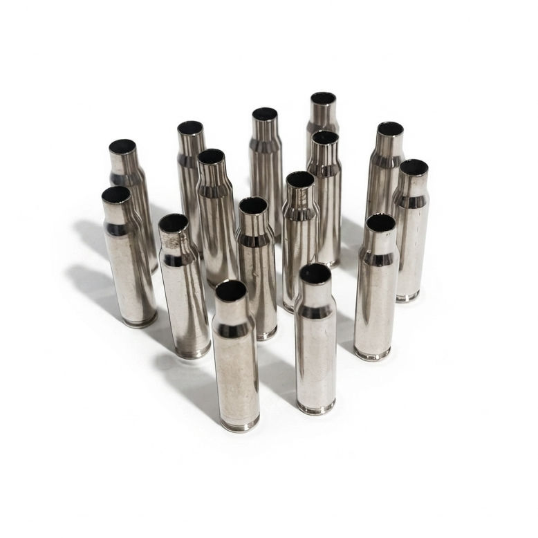Loosely spaced group of twelve empty silver .308 WIN shells standing upright on their bases on a plain white surface.