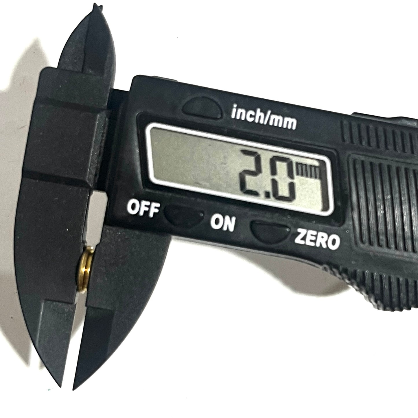 Digital caliper measuring the thickness of a deprimed brass bullet slice showing 2.0 mm