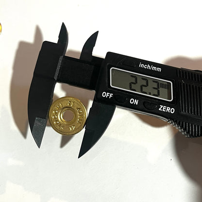 Digital caliper measuring a round brass 12 gauge Fiocchi headstamp slice at 22.3 mm diameter