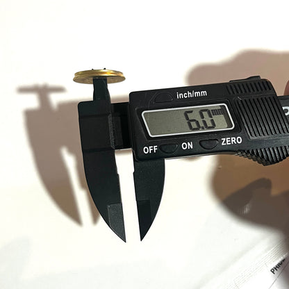 Digital caliper measuring the punched hole diameter of a brass 12 gauge shotgun shell slice at 6.0 mm