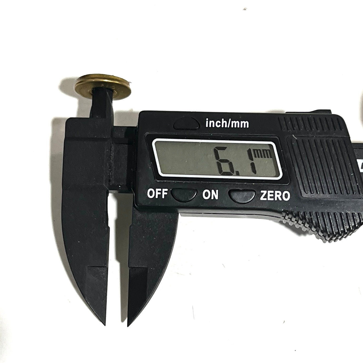 Digital caliper measuring a Fiocchi 28 gauge shotgun shell slice at 6.1 mm thick