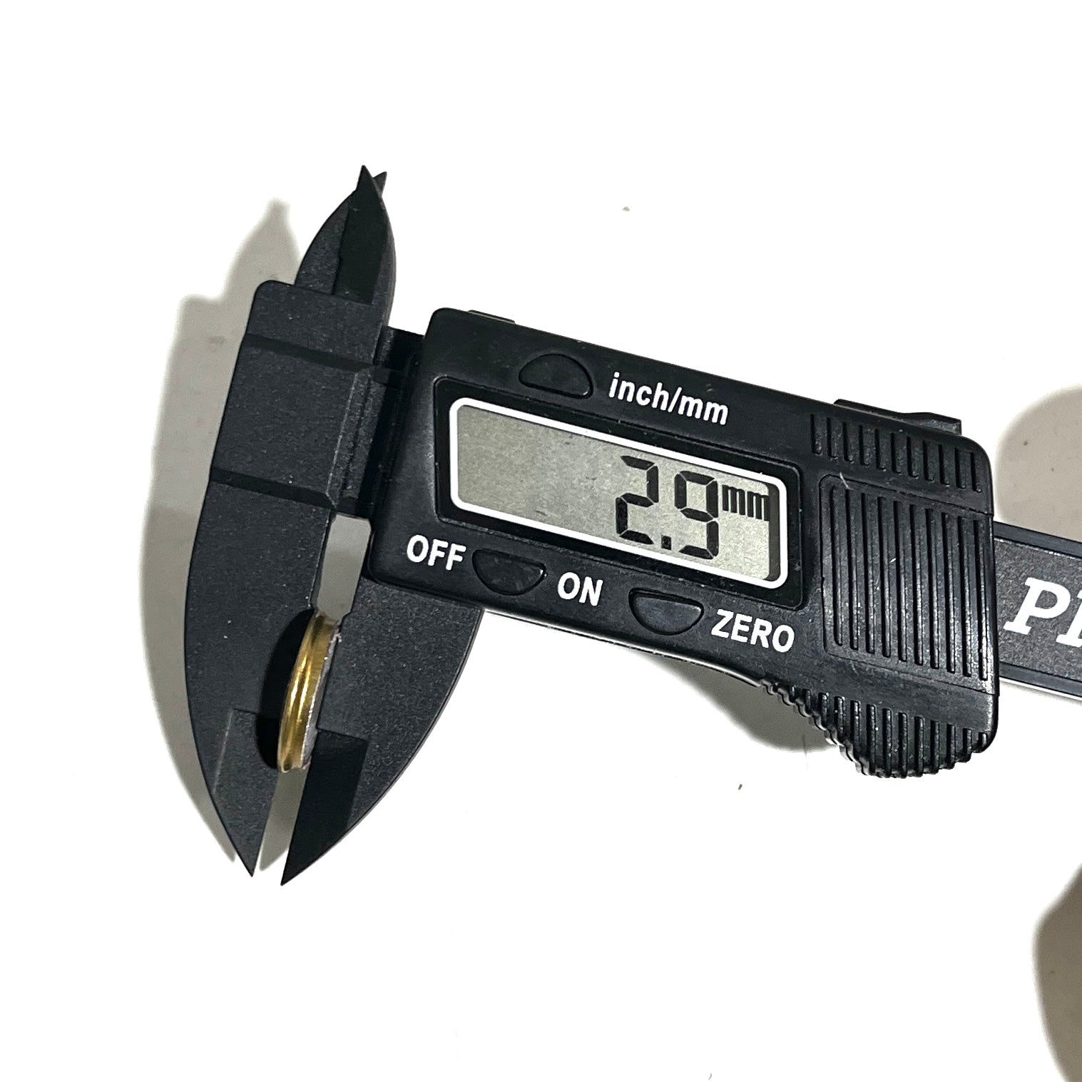 Digital caliper measuring a Fiocchi 28 gauge shotgun shell slice at 2.9 mm thick