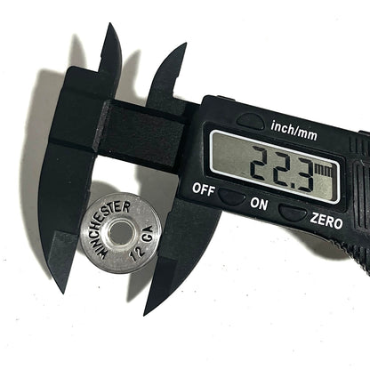 A digital caliper measuring the diameter of a silver hand painted Winchester 12 gauge shotgun shell slice on a white background.