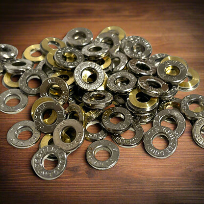 Pile of deprimed silver nickel 380 Auto casing slices on dark wood, showing readable Hornady and WIN headstamps.