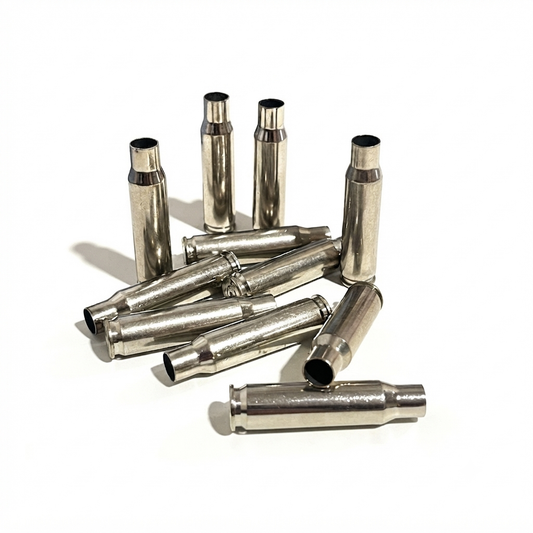 Mixed group of eleven empty silver polished inert .308 WIN casings on a white surface, with five standing upright and six lying flat.