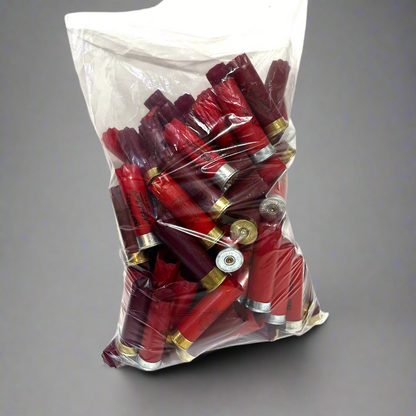 Clear plastic bag filled with mixed red and burgundy empty cartridges showing silver and gold bases on a gray surface.