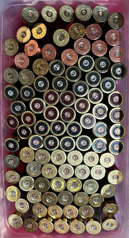 Bin filled with mixed shotgun shell brass bases in gold, copper, maroon, and black finishes, viewed from above