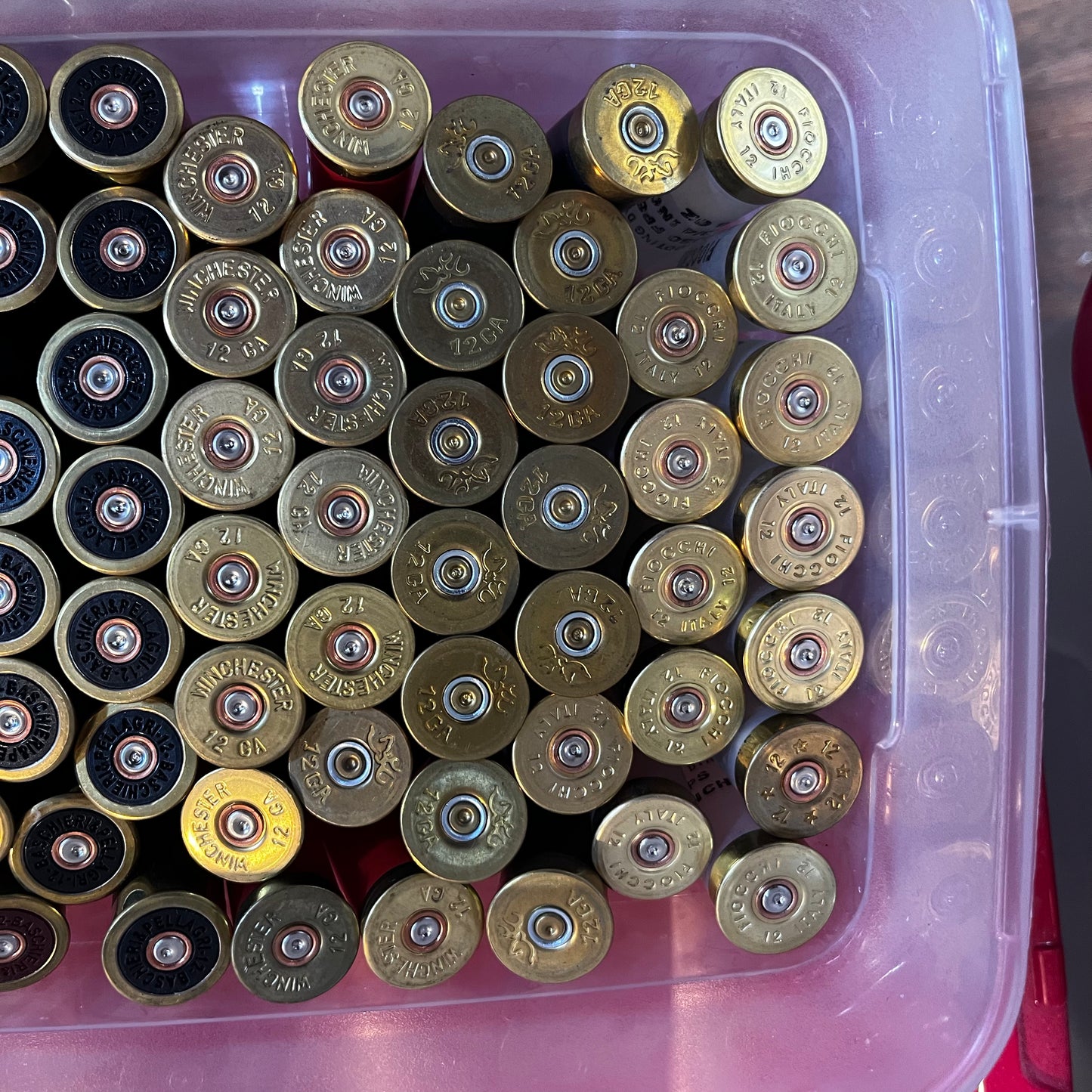 Bin filled with mixed shotgun shell brass bases showing 12 gauge and manufacturer headstamps, viewed from above